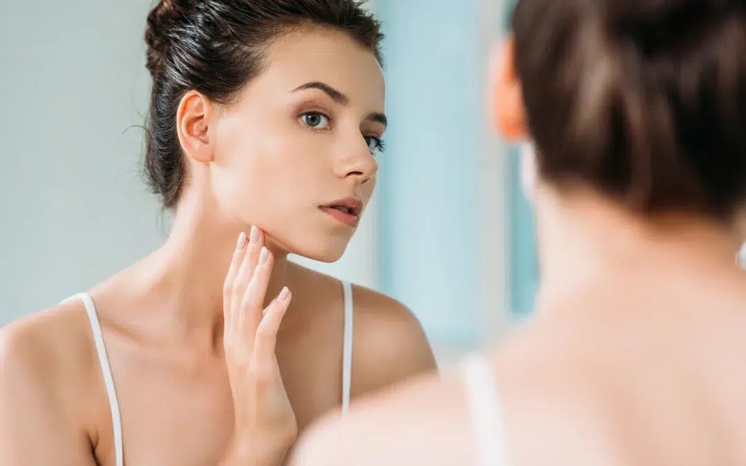 attractive woman touching face and looking at mirror
