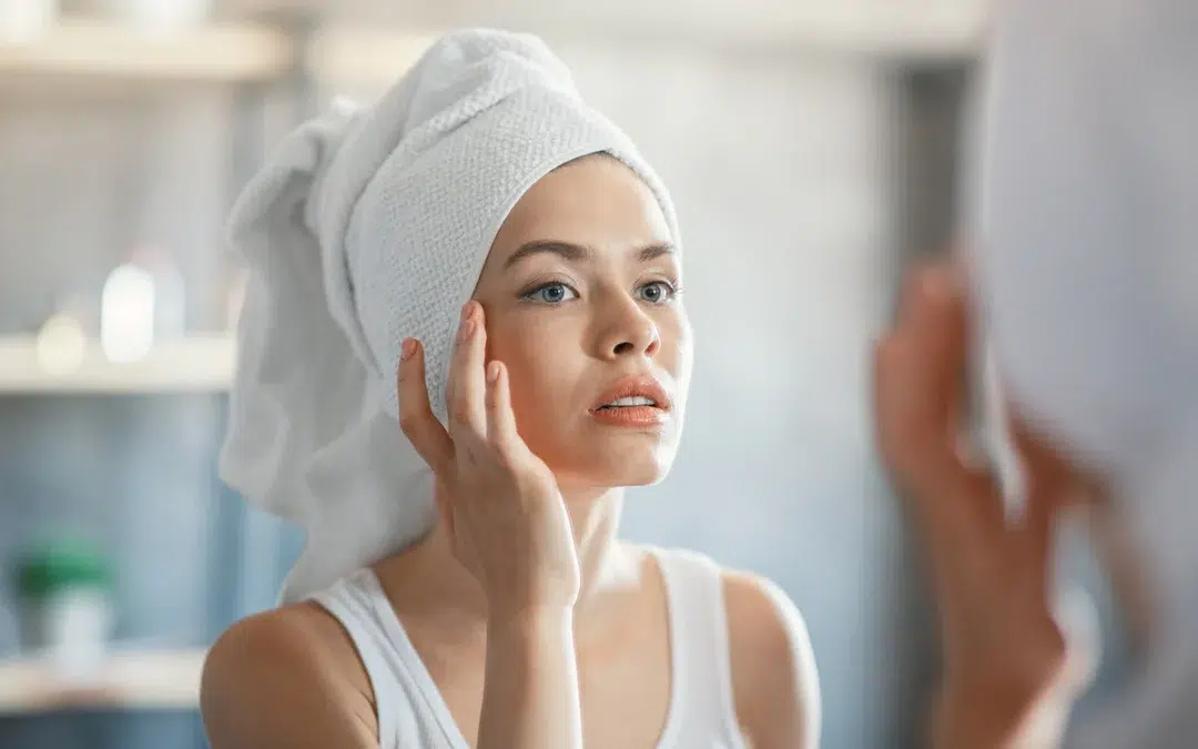 millennial woman touching her skin near mirror