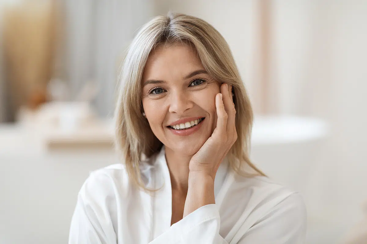portrait of smiling beautiful middle aged woman touching her cheek
