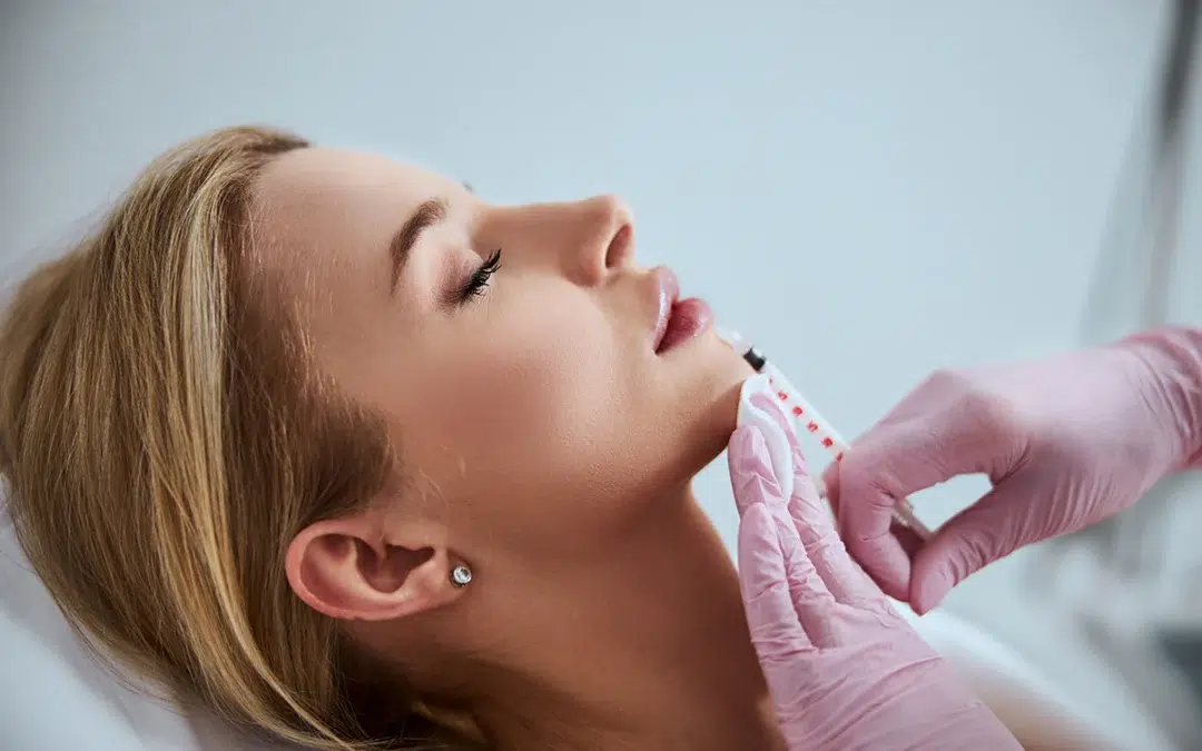 professional cosmetologist injecting a dermal filler into the patient lips