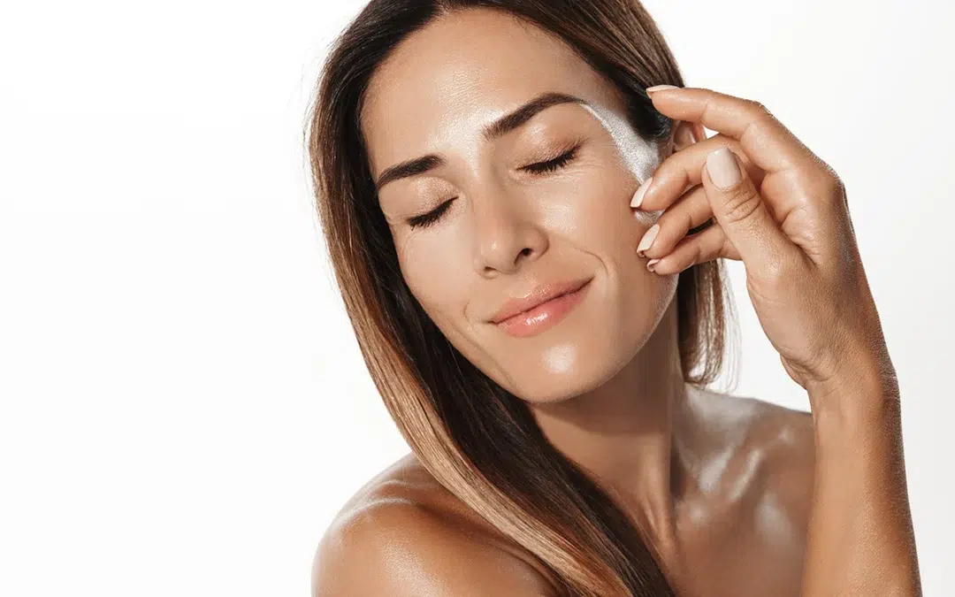 smiling middle aged woman touching her soft, glowing skin with pleasure