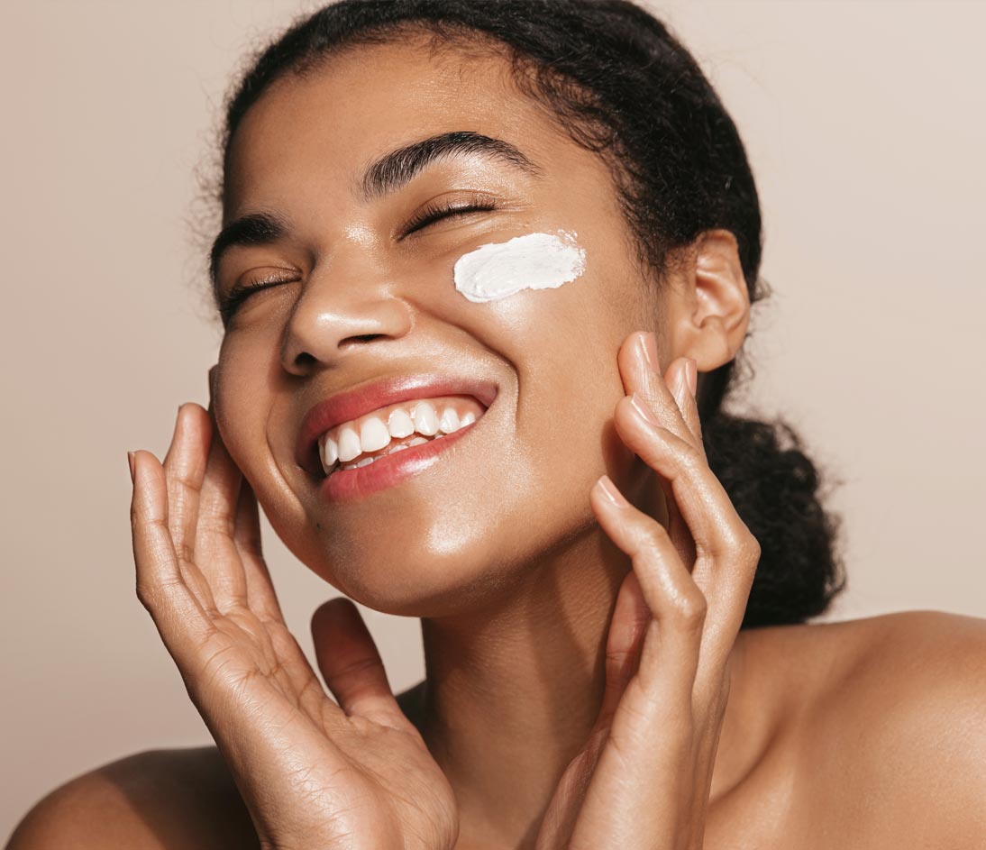 Smiling woman using skincare product. Female taking face cream to apply on facial skin
