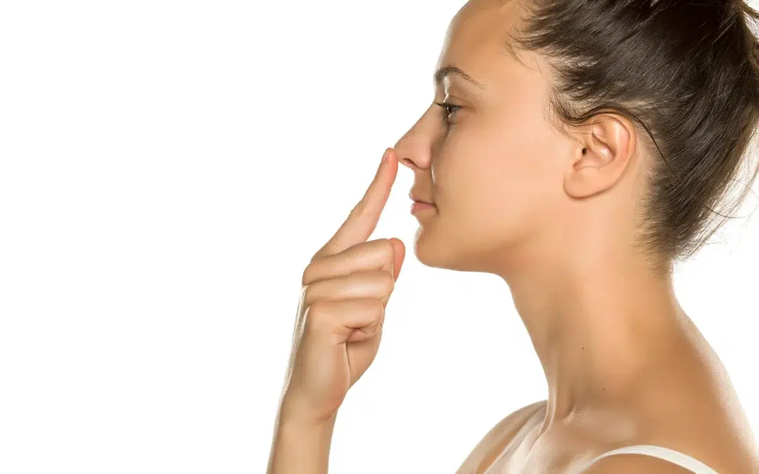 young woman touches her nose with her finger
