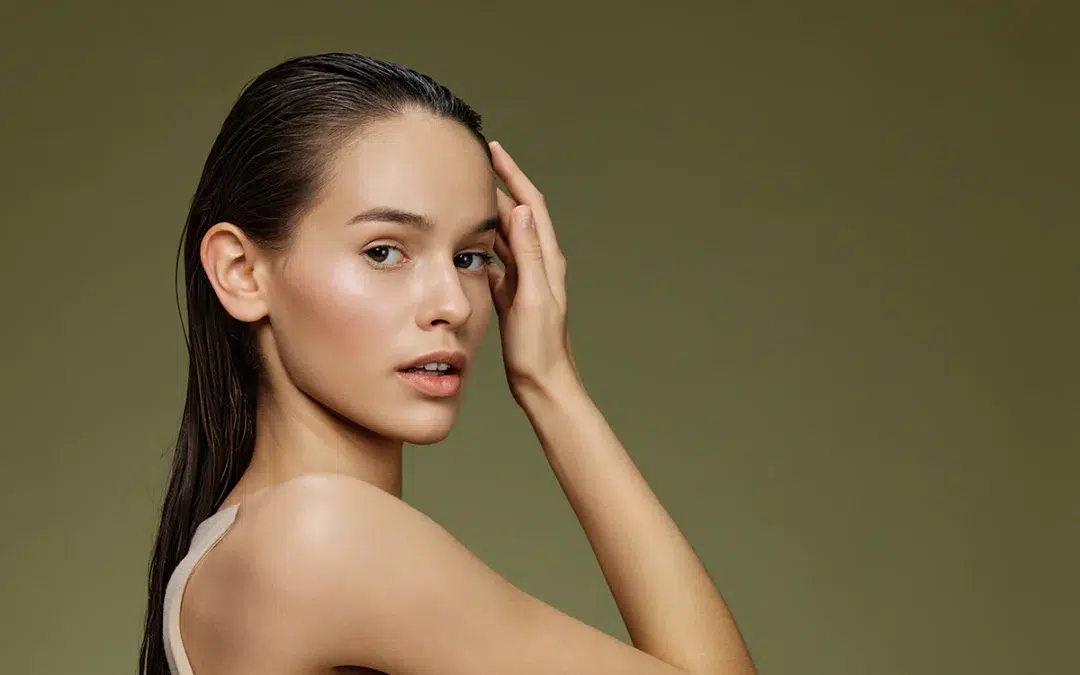 young woman with long wet hair touching her face