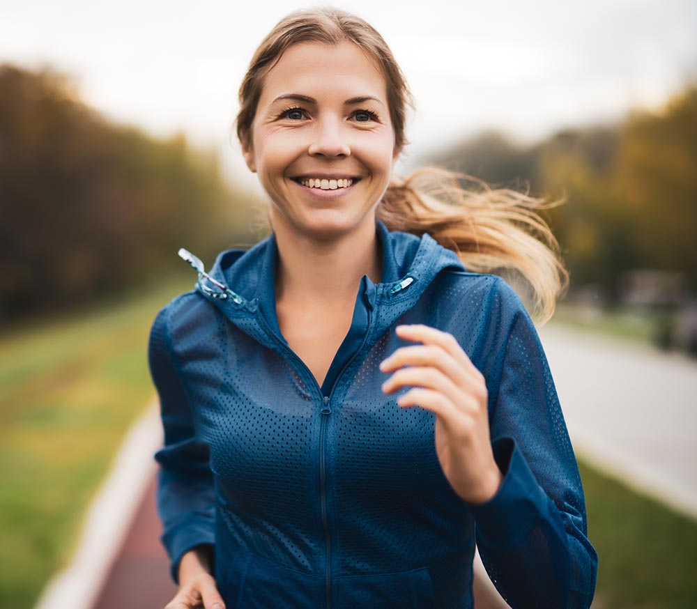 Beautiful adult woman is jogging outdoor on cloudy day in autumn