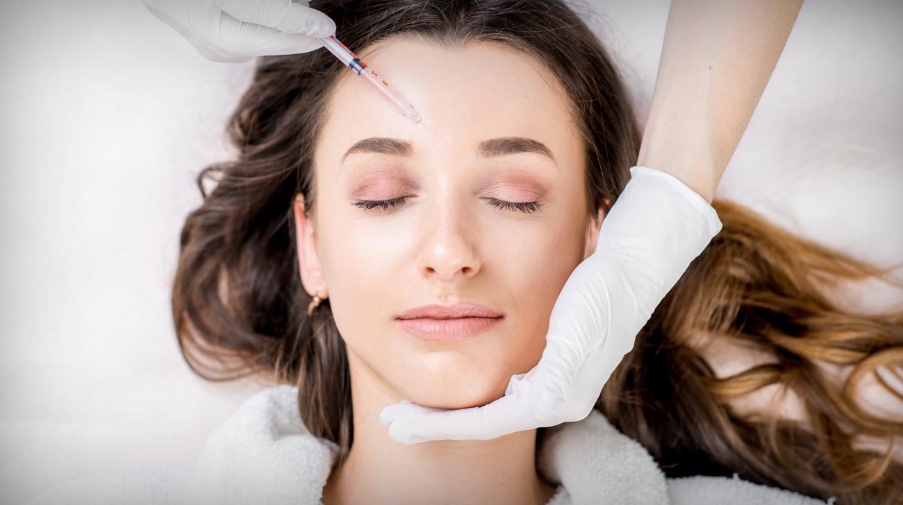 Woman receiving cosmetic injection in forehead