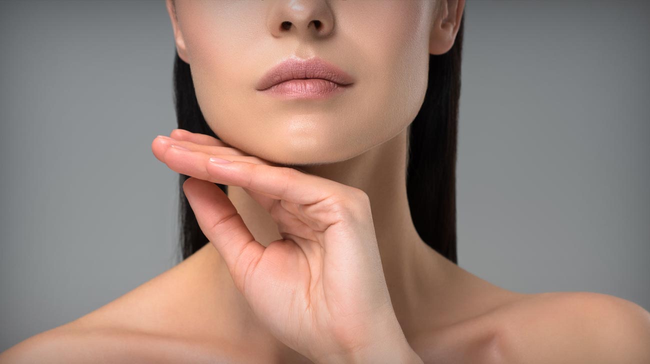 cropped shot of young naked brunette woman touching chin isolated on grey