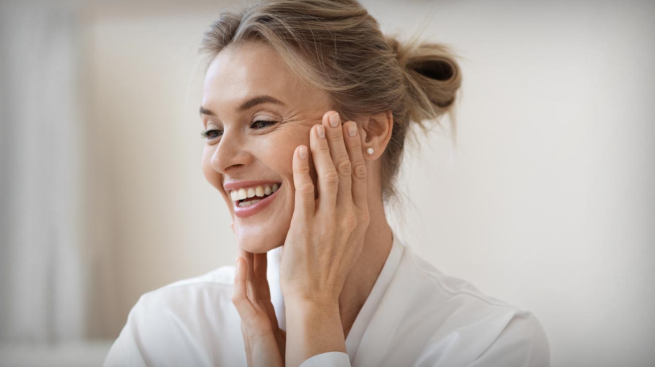 Smiling blonde woman making anti-aging face massage