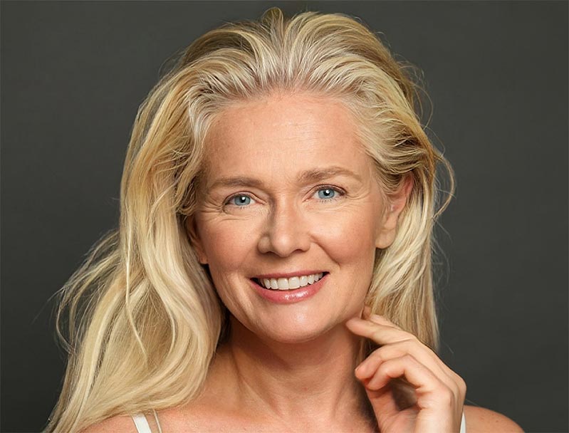Portrait of gorgeous happy blonde middle aged mature woman, senior older 50s on black background.