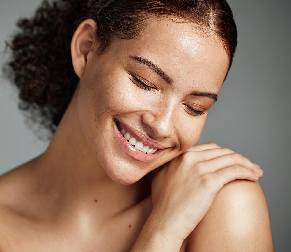 Face, beauty and skin with a model black woman in studio on a gray background to promote natural care. Facial, wellness and makeup with an attractive young female happy with her skincare product