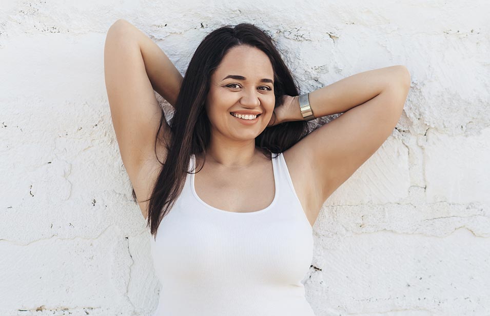 Plus size model dressed in white shirt posing over brick wall