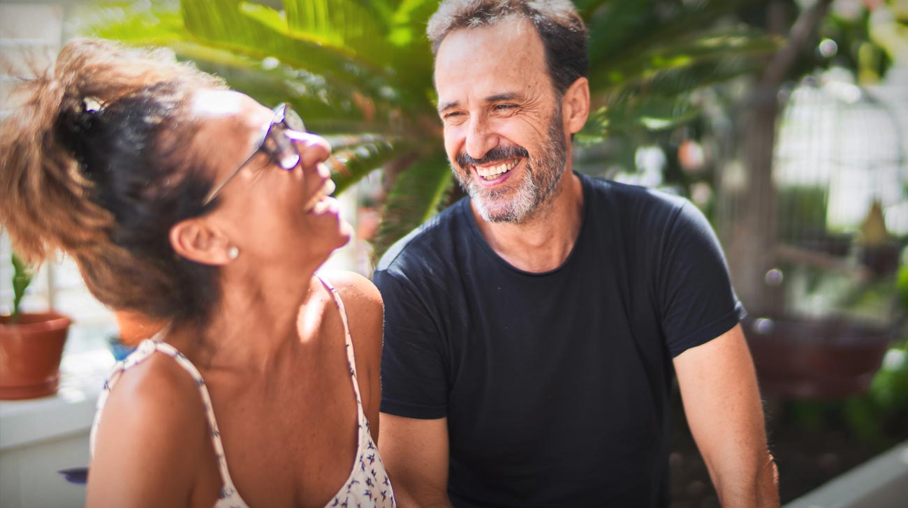 Middle age beautiful couple sitting on terrace speaking and smiling