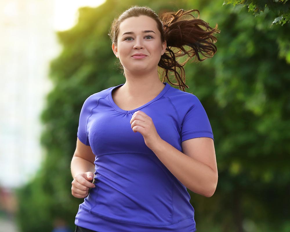 Overweight young woman jogging in the street. Weight loss concept