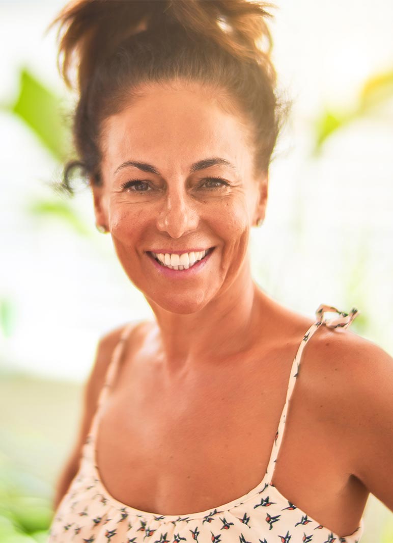 Middle age beautiful woman standing on terrace with plants smiling