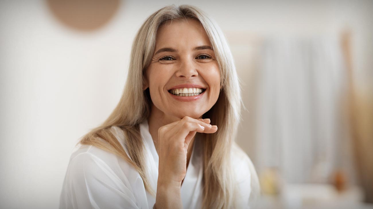 Happy blonde woman posing at white bathroom at home