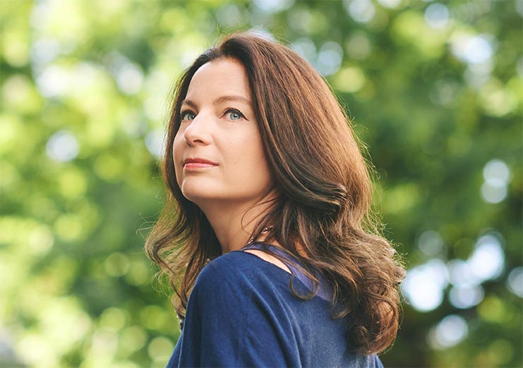 Outdoor portrait of beautiful mature year old woman with brown hair, looking back over the shoulder
