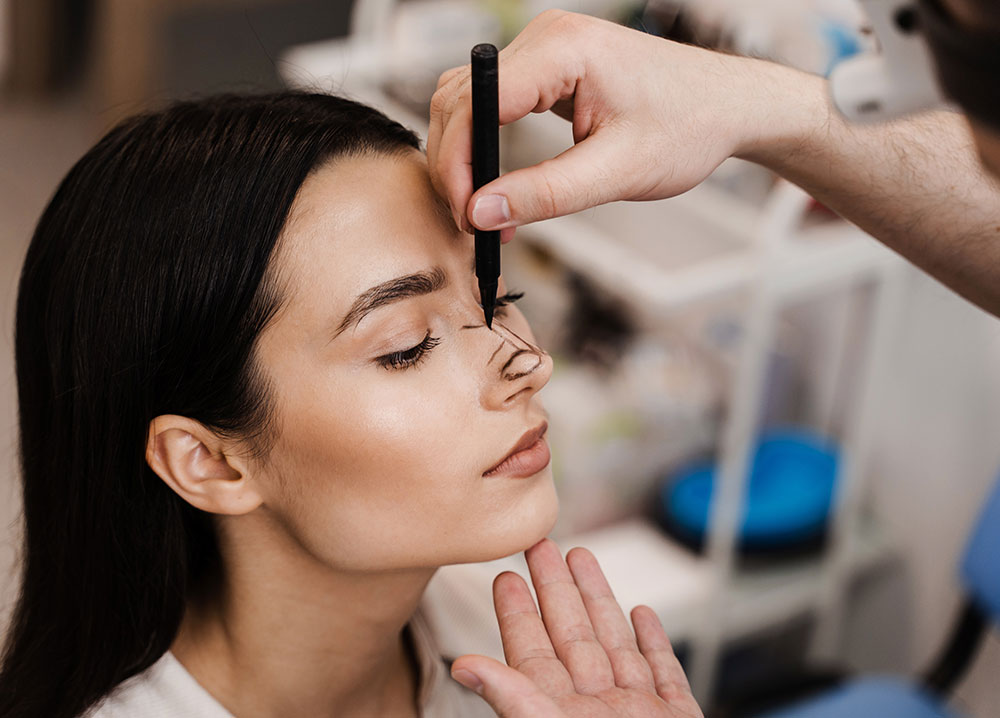 ENT doctor is drawing mark up lines on nose before rhinoplasty surgery. Rhinoplasty markup. Rhinoplasty is reshaping nose surgery for change appearance of the nose and improve breathing.